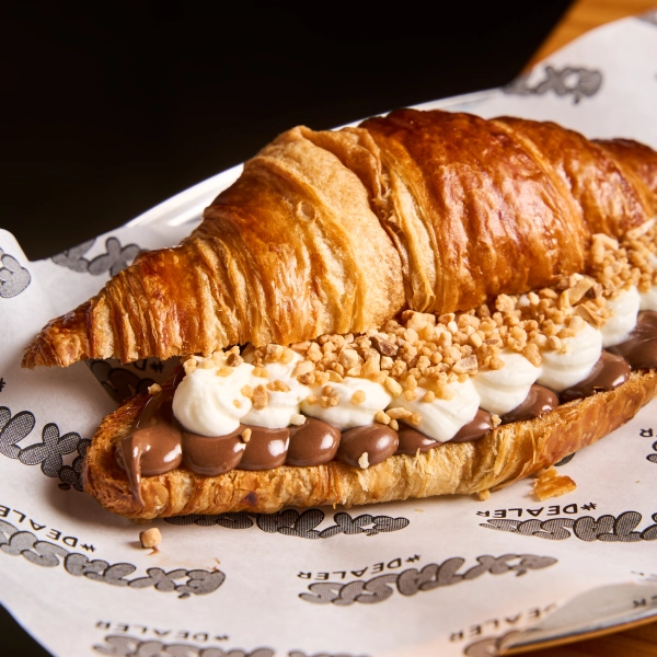 Croissant de mantequilla tostado relleno de nutella, nata montada por nosotros y almendra caramelizada. Puro postureo bro.